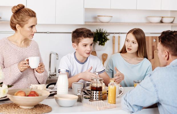 parents and young teen boy and girl at breakfast and talking